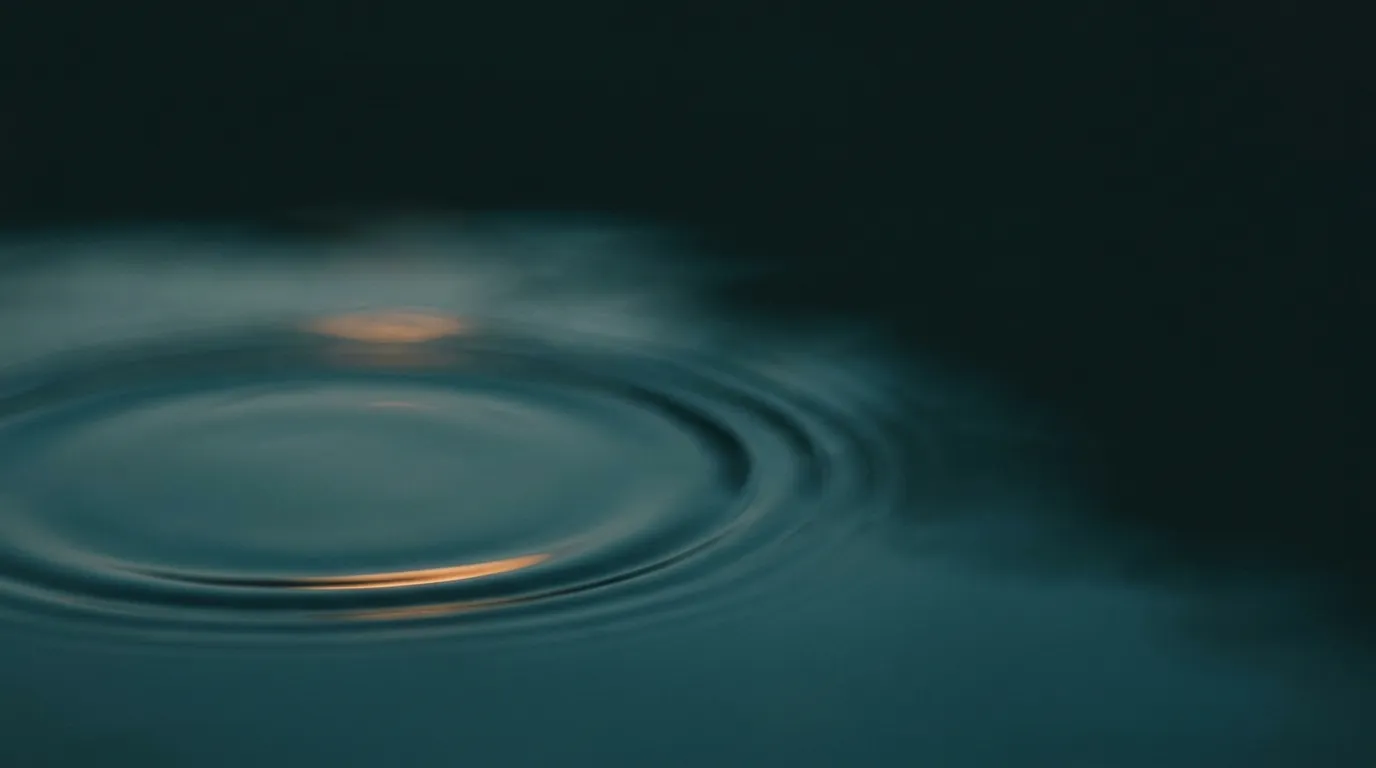 Konzentrische Wellenringe breiten sich ruhig über dunkles Wasser aus, ausgehend von einem warmen Lichtpunkt.