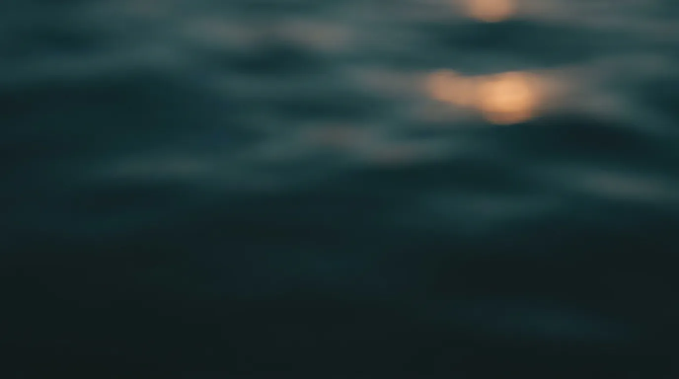 Sanfte Wellen auf dunklem Wasser, auf denen sich warmes Abendlicht in kleinen Reflexen wiederholt.