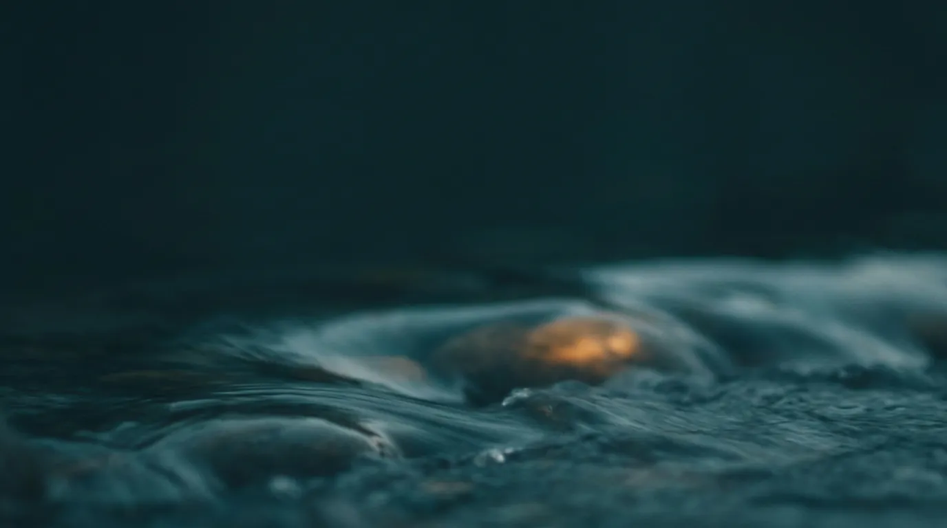Bewegtes, schäumendes Wasser, durch das ein warmer Lichtschein bricht.